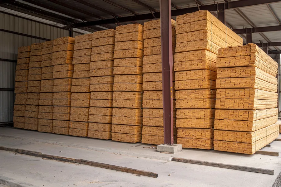 Große Stapel gesägter Holzbretter lagern in einer Lagerhalle.