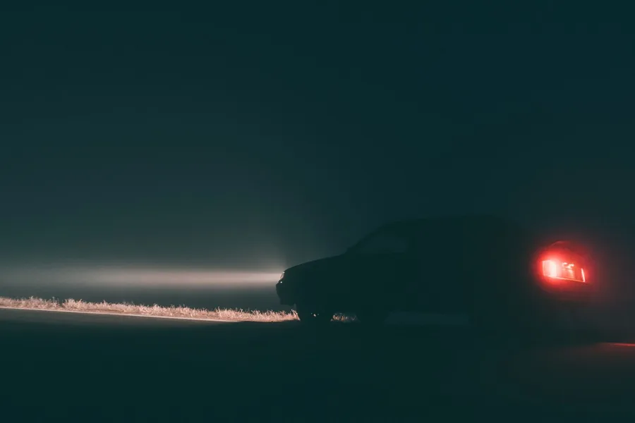 Ein Auto steht mit rot leuchtendem Rücklicht auf einer nächtlichen Landstraße im Nebel