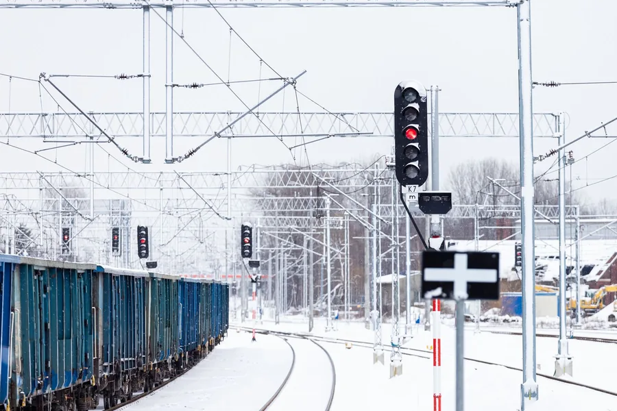 Güterzug mit Waggons neben einem roten Signal auf verschneiten Gleisen
