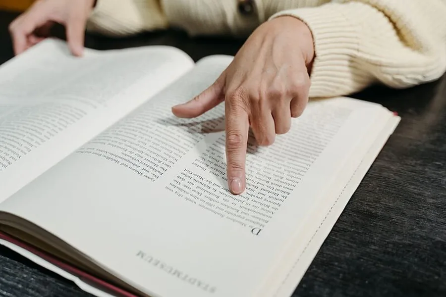 Ein Finger zeigt auf eine Textstelle in einem aufgeschlagenen Buch