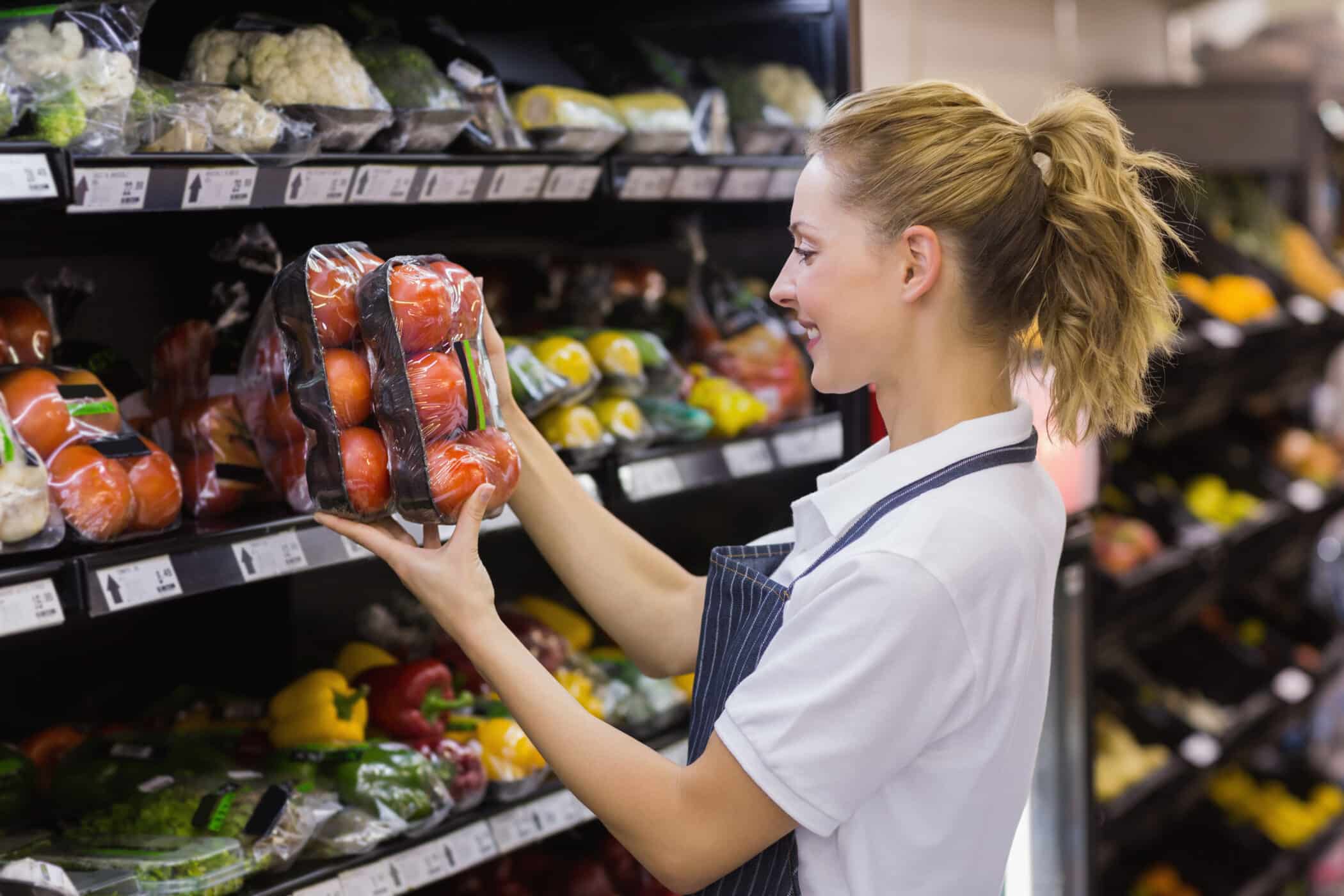 Employee picking up produce in small retail shop 