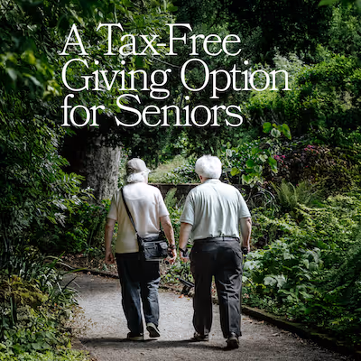 Two seniors walking through a green park with text that says, "A tax-free giving option for seniors."