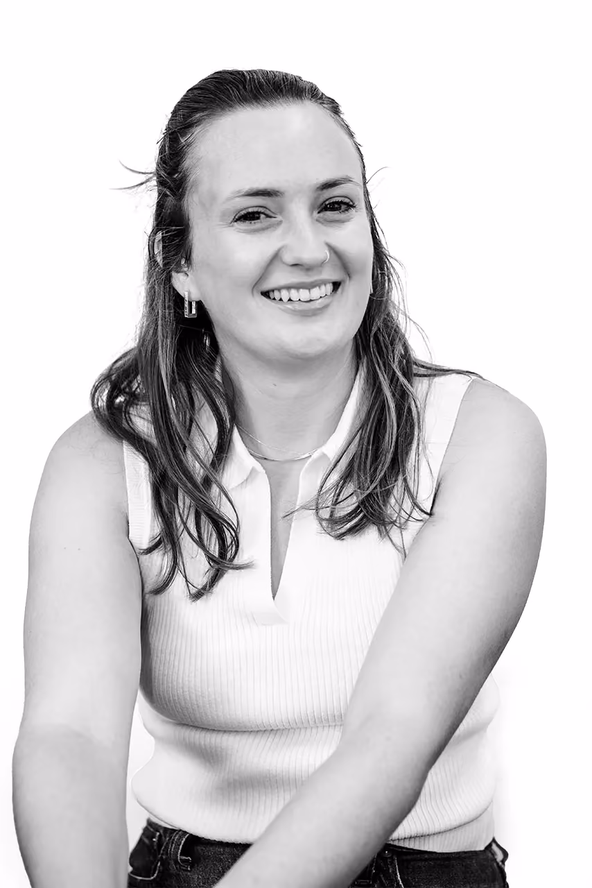 Smiling woman with long hair wearing a sleeveless white top and earrings against a white background.