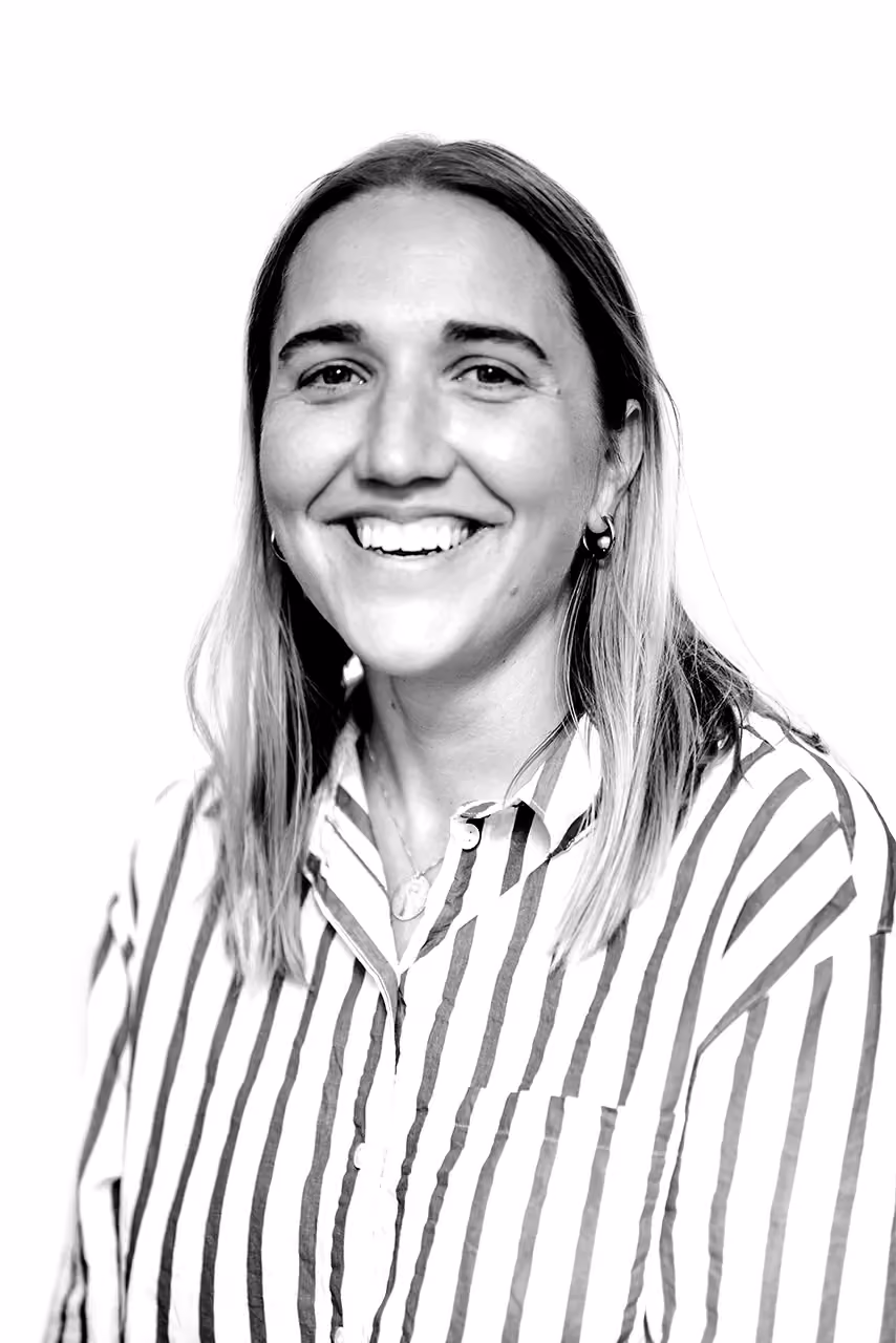 Smiling woman with shoulder-length hair wearing a striped button-up shirt and hoop earrings.