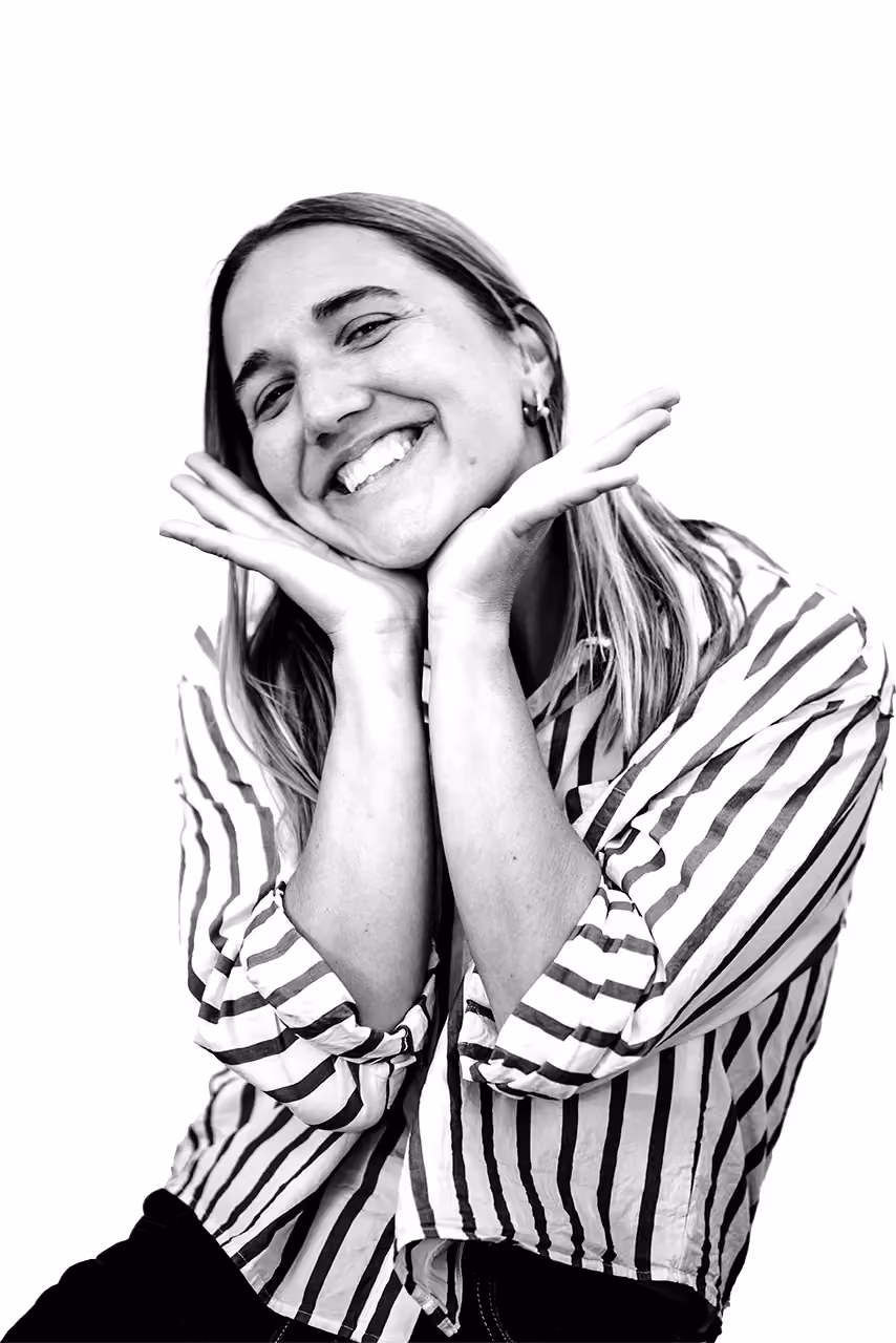 Smiling woman in striped shirt poses with hands framing her face, expressing joy.