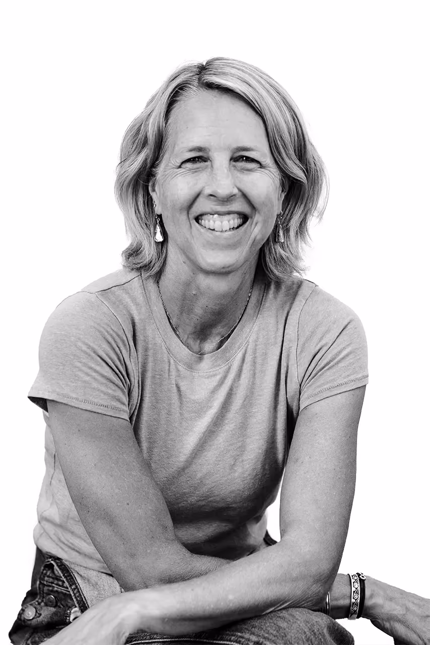 Smiling woman with short light hair wearing earrings, a t-shirt, and bracelets on one wrist.