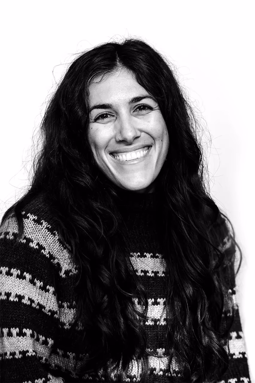 Smiling woman with long dark hair wearing a patterned sweater in black and white photo.