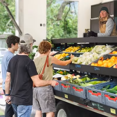 Three people looking at fresh produce at a food bank.