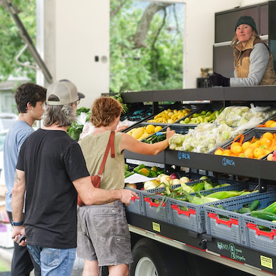 Three people looking at fresh produce at a food bank.