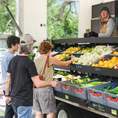 Three people looking at fresh produce at a food bank.