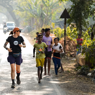 Woman running along children in a street in India.