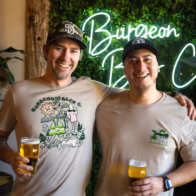 Two people smiling and holding beers.