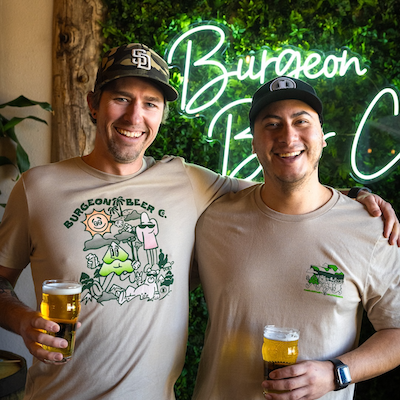 Two people smiling and holding beers.