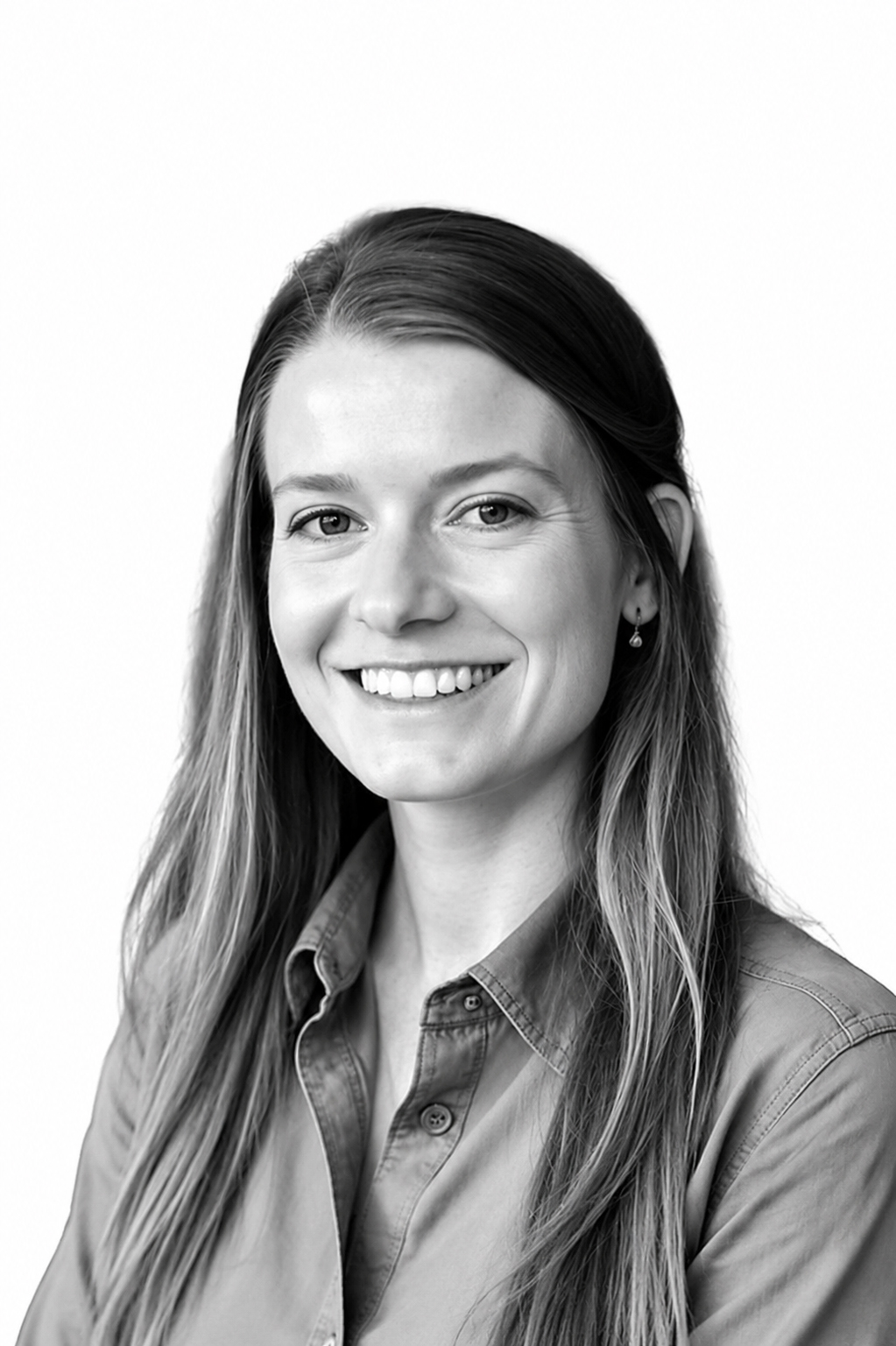 Smiling woman with long hair wearing button-up shirt against a plain white background.