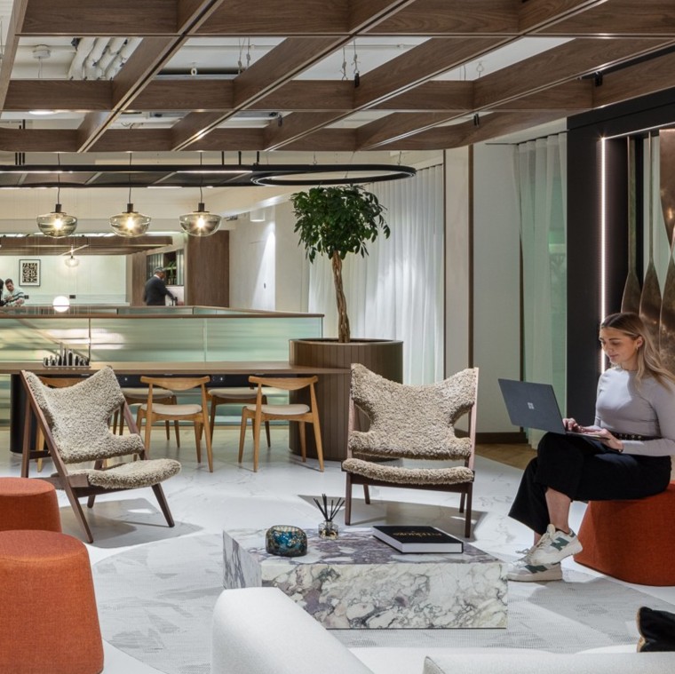 An cosy office space, with a girl sitting and working on her laptop