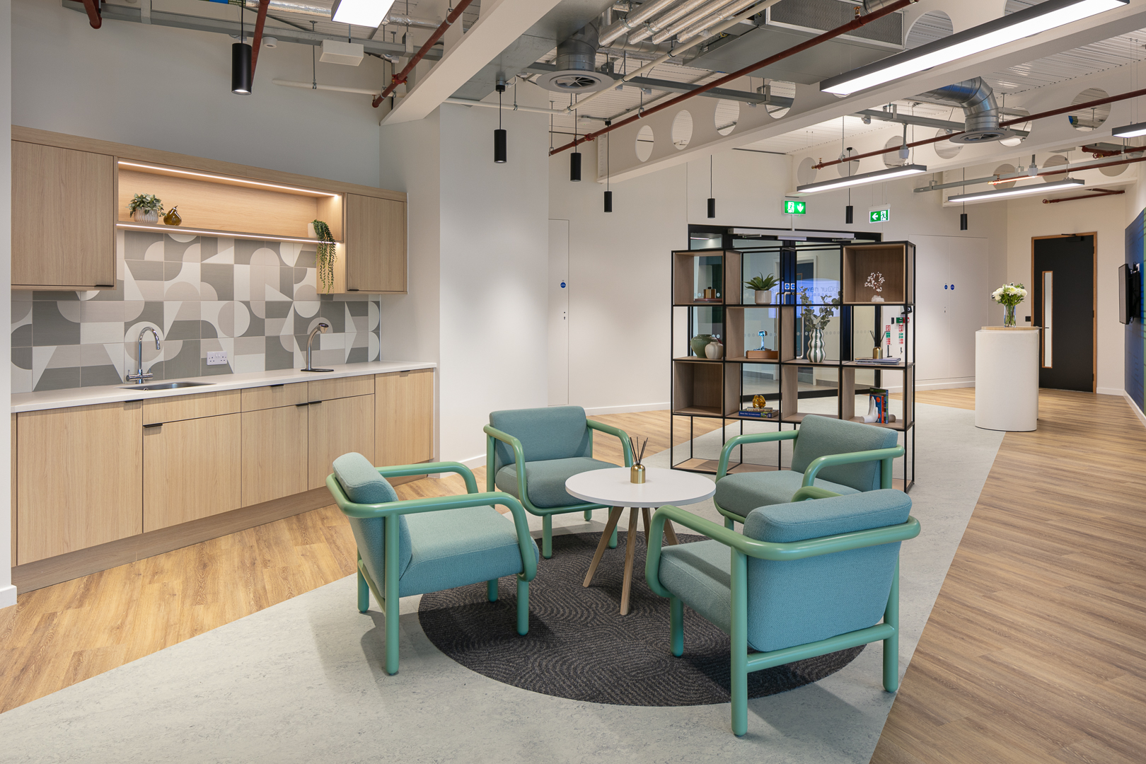 An office reception with chairs, a coffee table and a kitchen