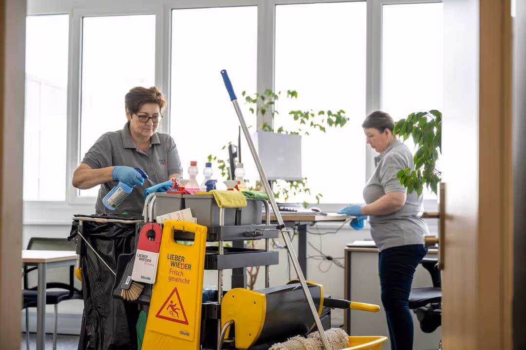 Zwei Büroreinigungskräfte eines integrativen Betriebe bei ihrer Tätigkeit.