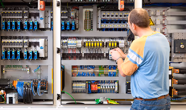 Ein Mitarbeiter eines integrativen Betriebs arbeitet an einem Elektroschaltschrank.