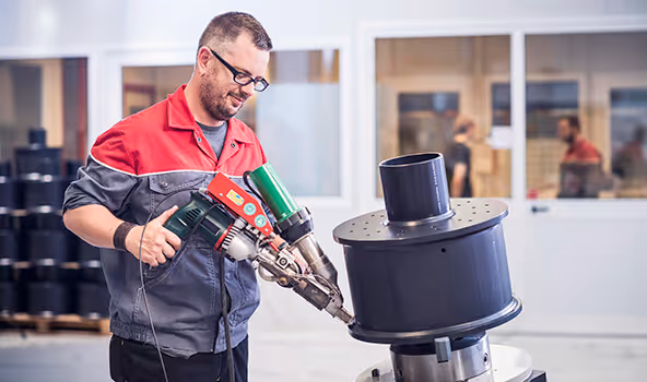 Dieser Mitarbeiter eines integrativen Betriebs bearbeitet ein Bauteil aus Hochleistungskunststoff und führt auch eine Dichtheitsprüfung durch.
