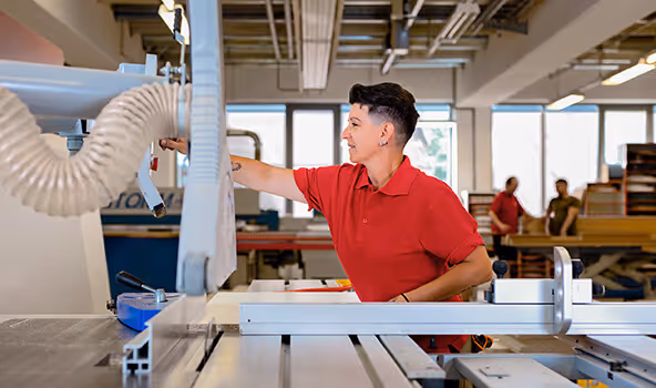 Eine Arbeiterin eines integrativen Betriebs bedient die Säge in der Tischlerei.