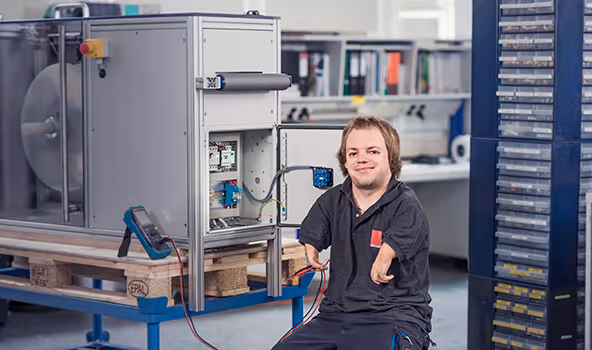 Eine Fachkraft des integrativen Betriebes beim Messen mechatronischer Bauteile im ESD-Labor.