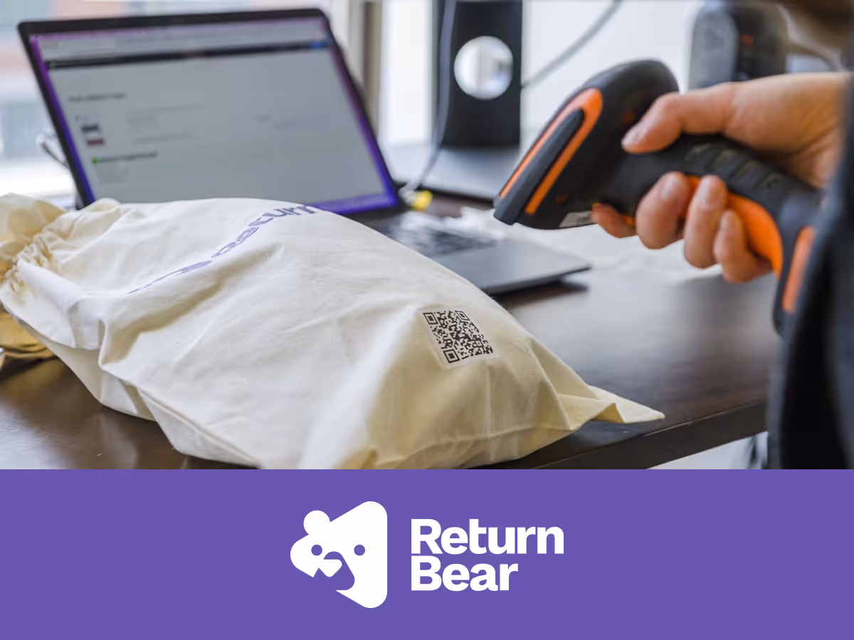 A hand holding a barcode scanner scanning a code on a Return Bear bag