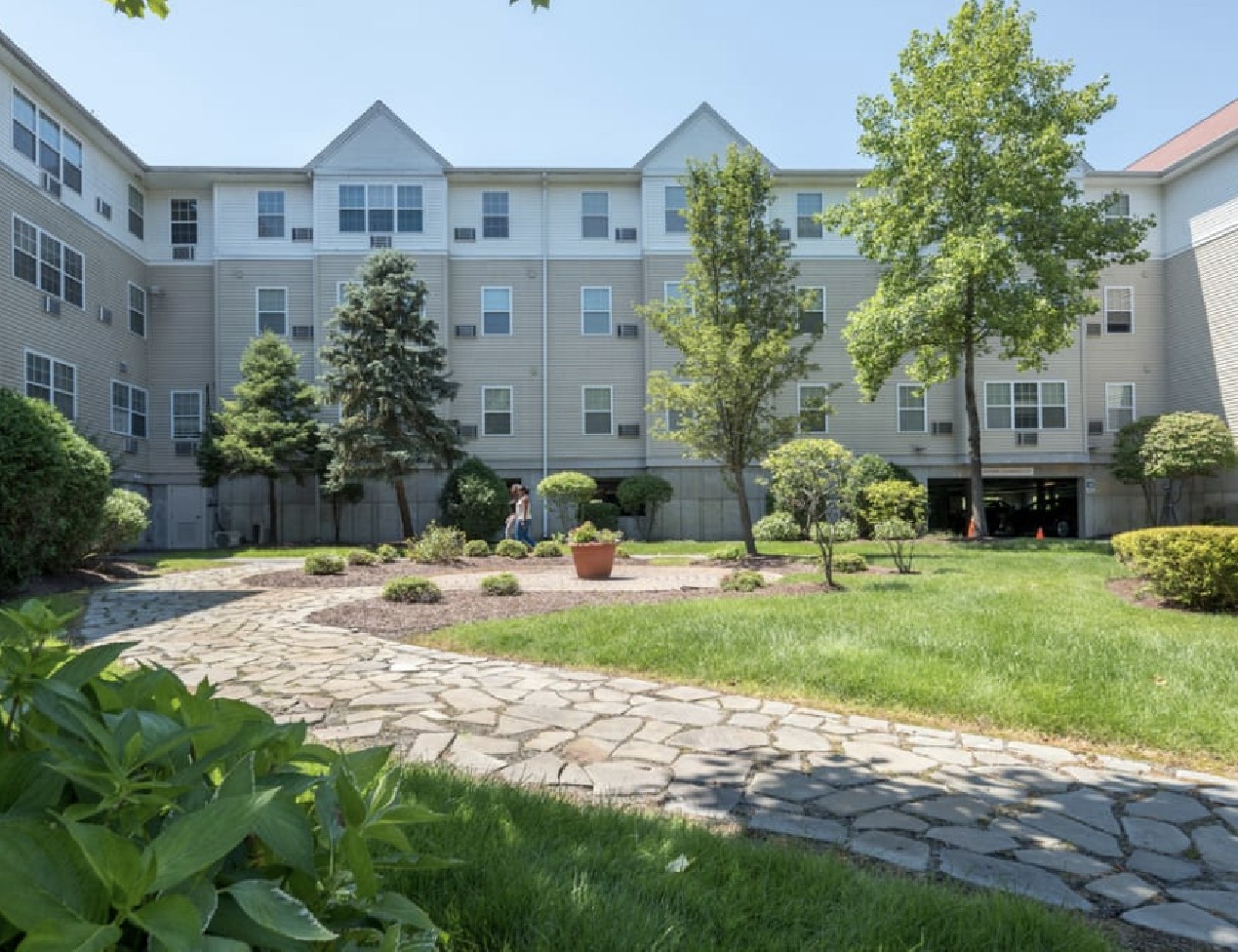 An apartment community with a grassy lawn and some trees