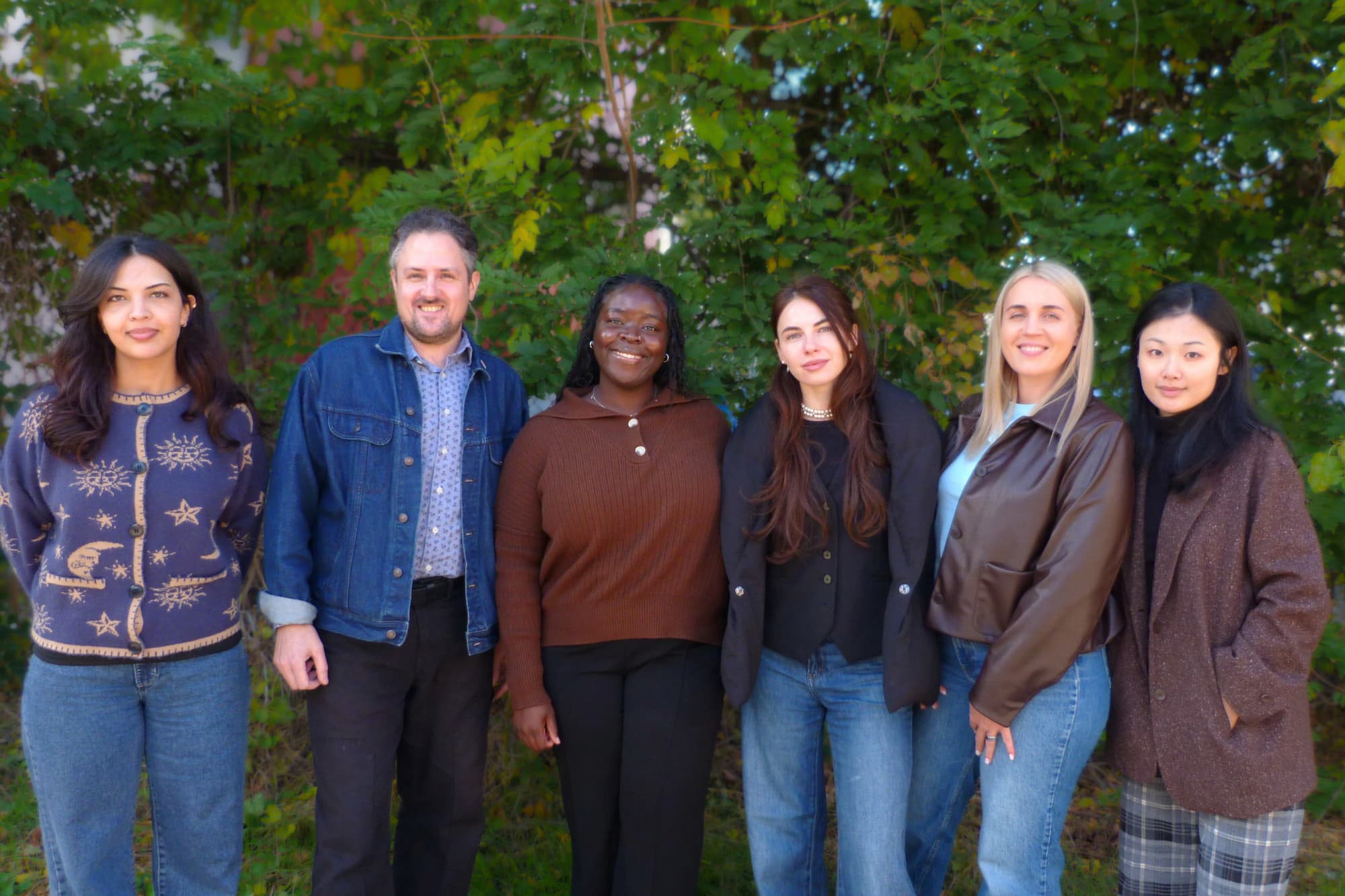 Hello Neighbor's Employment team posing for photo outside surrounded by leafy foliage