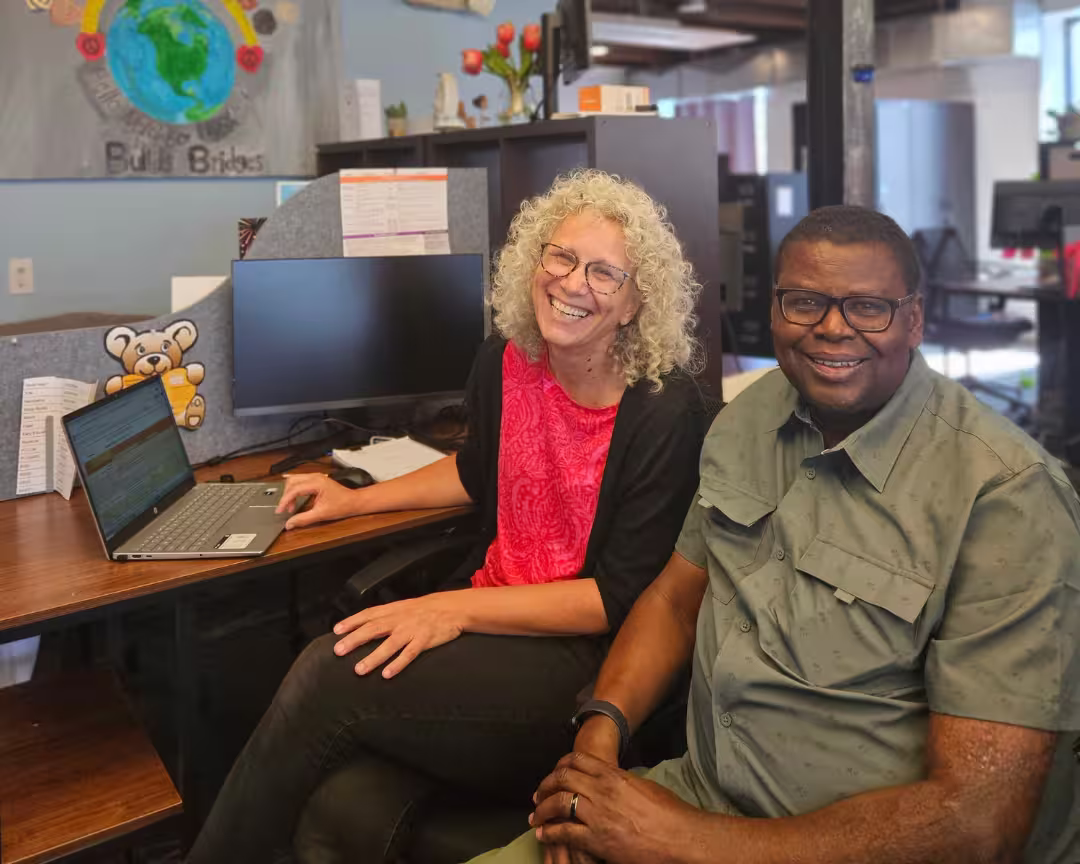 Two smiling members of the Intensive Case Management team pictured at an office desk.