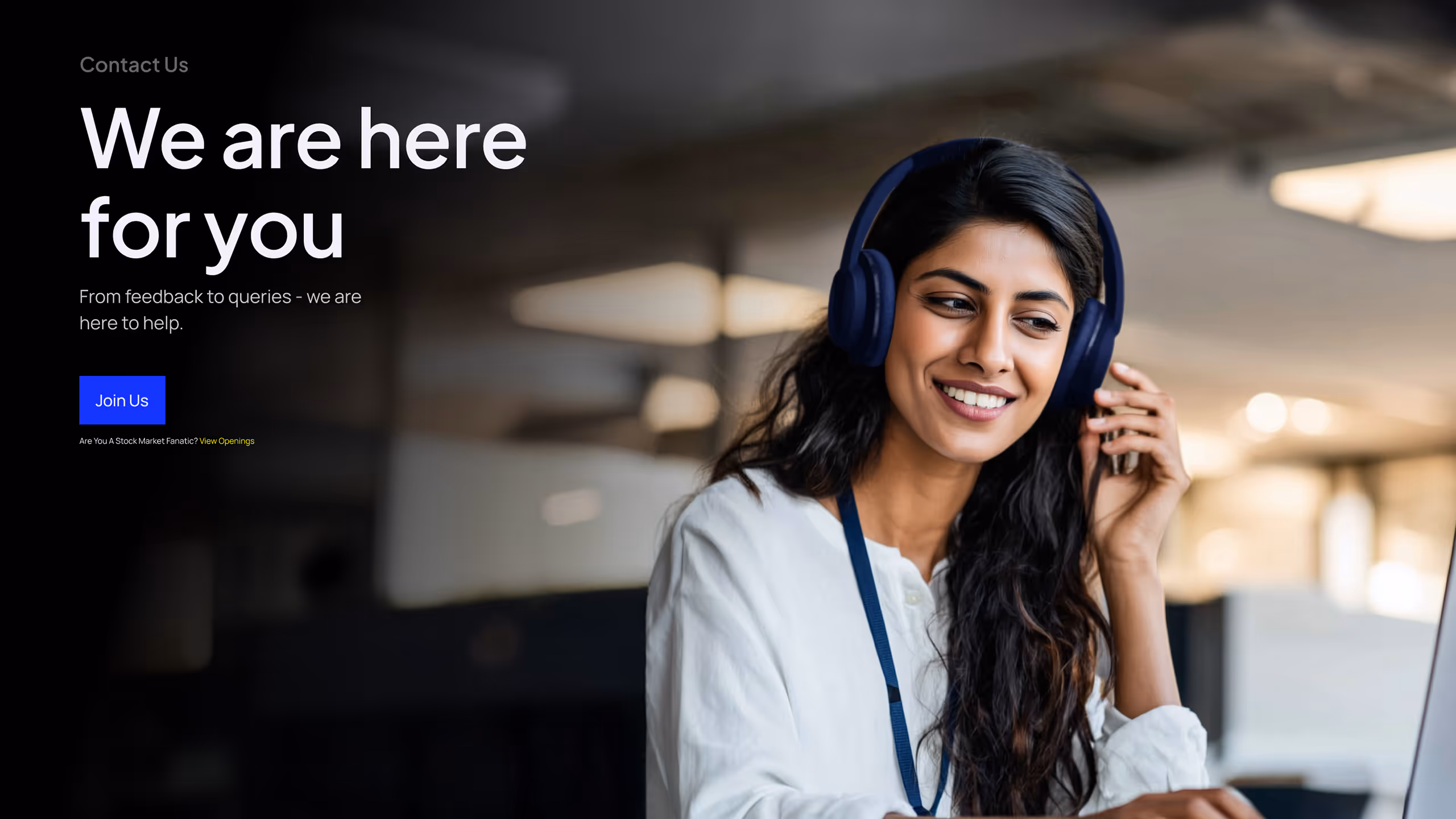 Smiling woman wearing headphones and a white shirt, working on a laptop in a modern office.