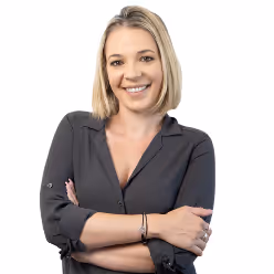 Smiling woman with blonde hair wearing a dark button-up shirt with arms crossed.