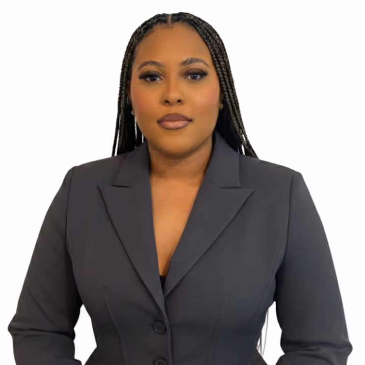 Confident woman with straight black hair, red lipstick, and crossed arms wearing a black cardigan and a heart-shaped necklace.