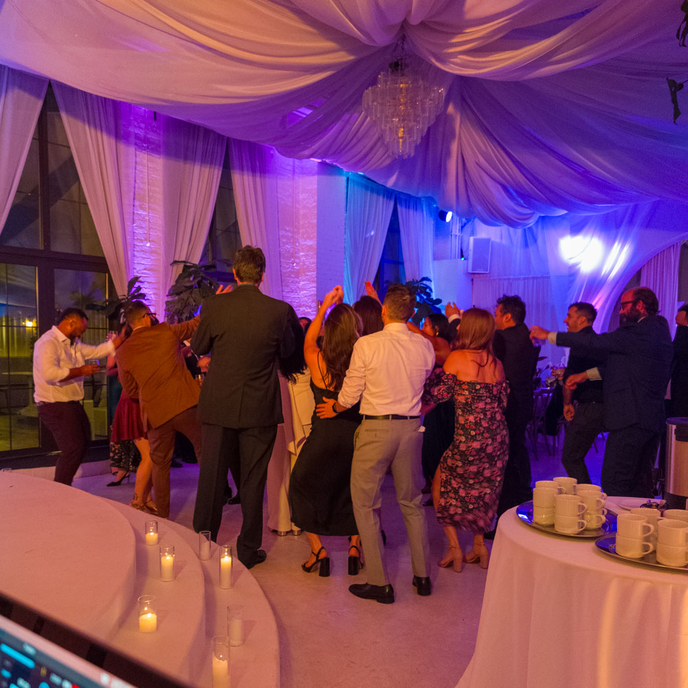 Micro‑wedding reception — full dance floor with colorful uplights in music mode; guests dancing and celebrating.