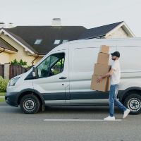 A man is walking down the street carrying a box.