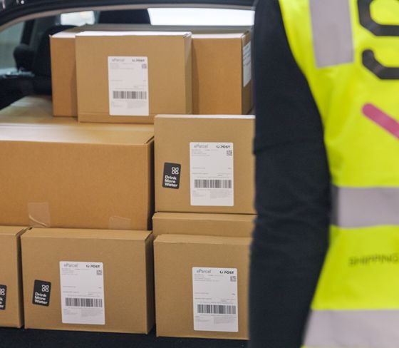 A person wearing a yellow vest is standing next to a stack of boxes.