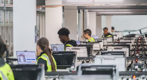 A group of people working on computers in a factory.