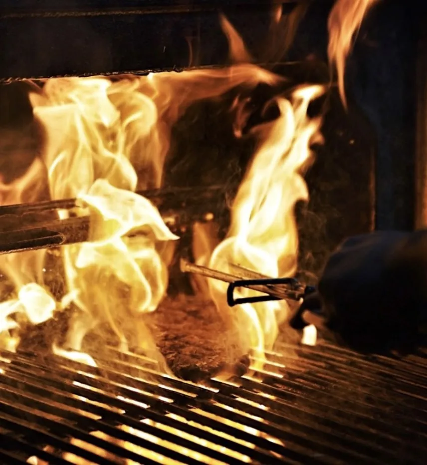 Charcoal Grilling Beef Steak with Flames over it an example of First Grill Grilled Food Singapore