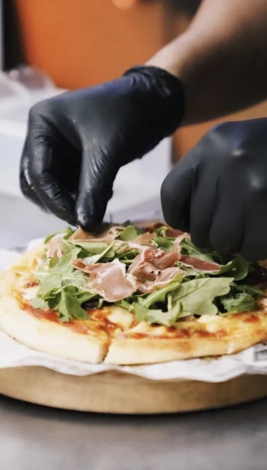 Man laying out ingredients for Bacon Meat Pizza an example of First Grill Food Singapore