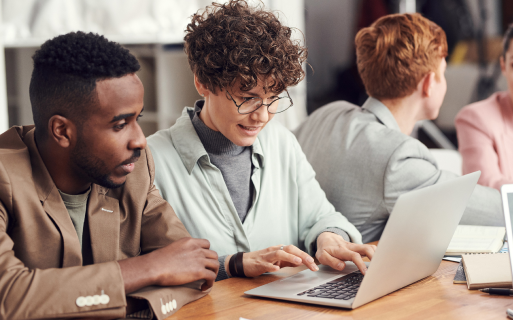 A woman with glasses is typing on a laptop.