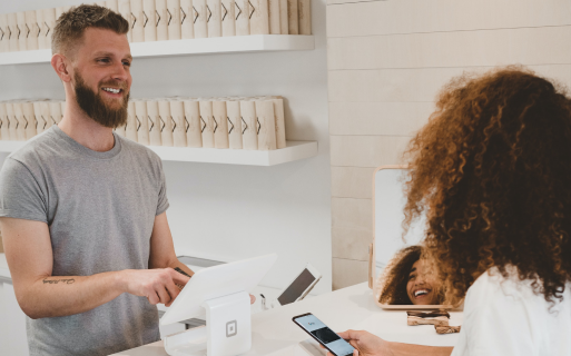 A man is smiling at a woman while holding a cell phone.