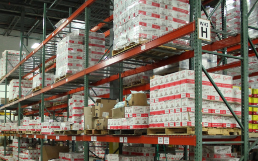A large warehouse with boxes of items on a red shelf.