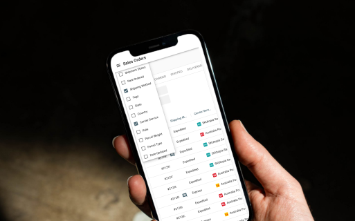 A person holding a cell phone with a list of sales orders.