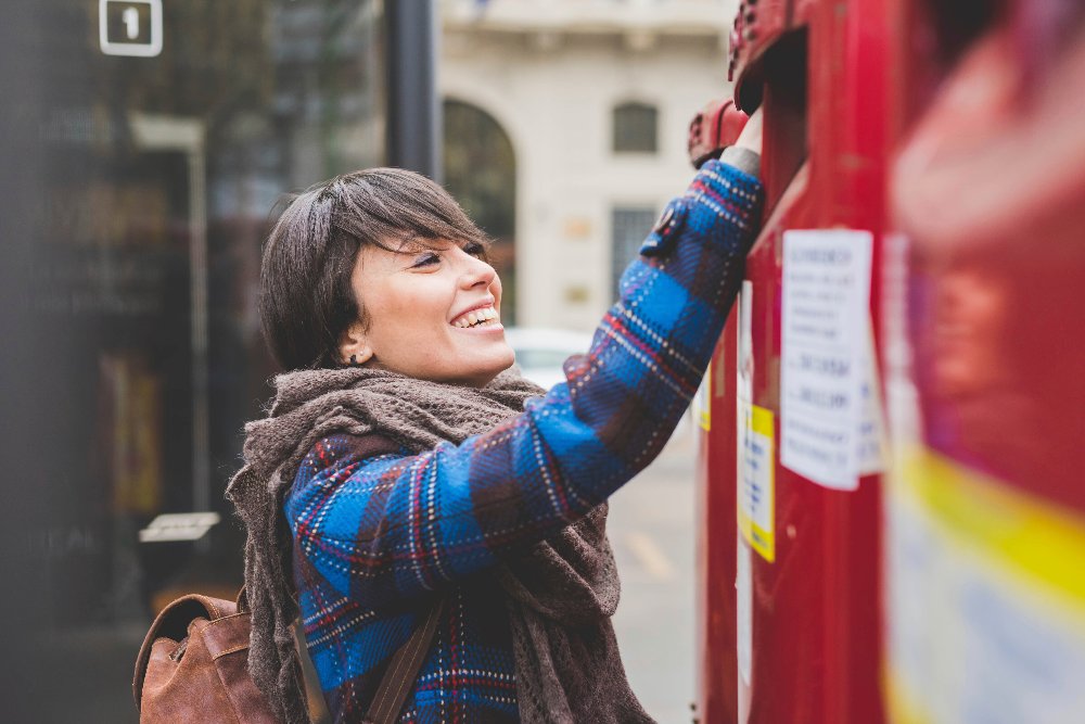 A woman with a brown scarf and a blue coat is smiling.
