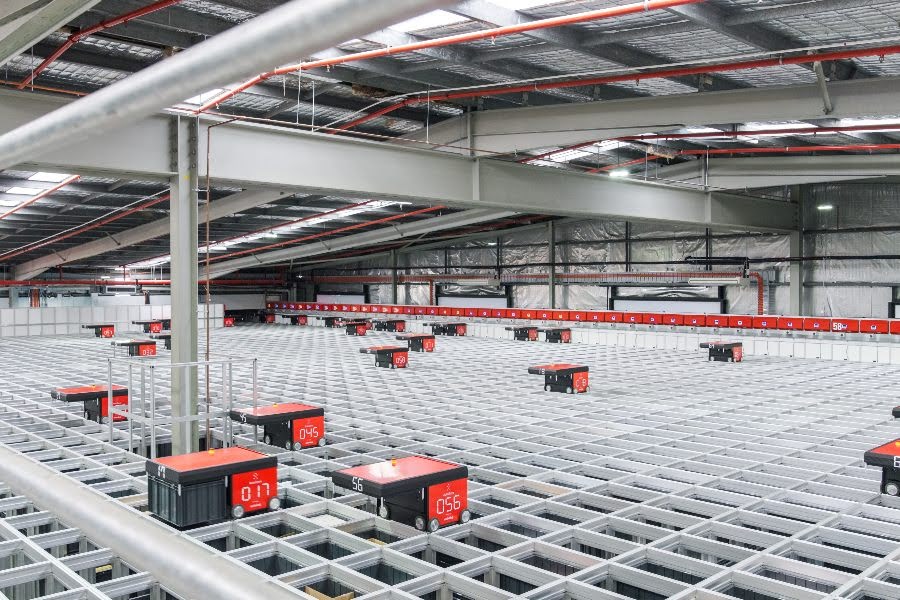 A large warehouse with many red boxes and a metal fence.