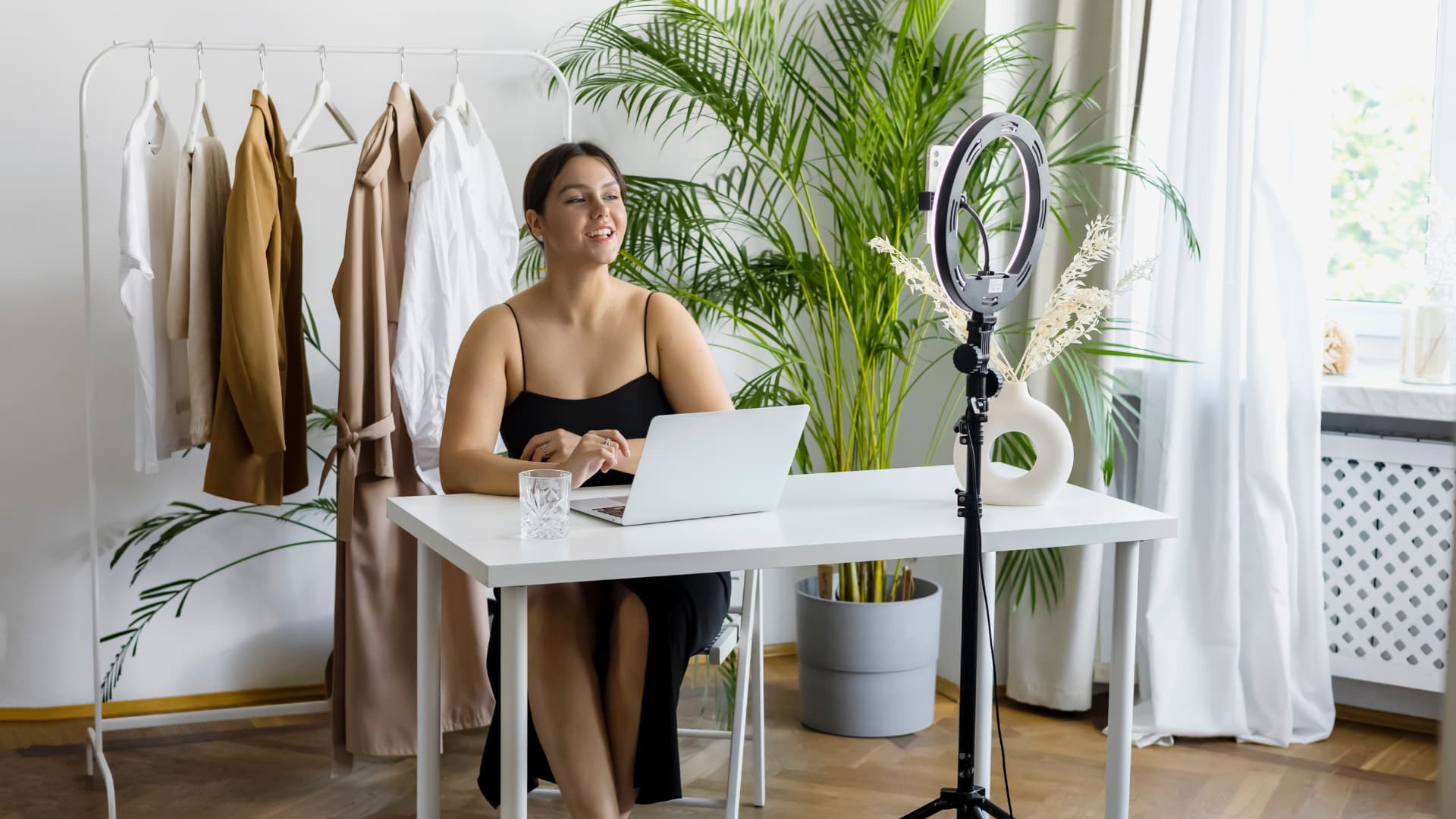 A woman sitting at a desk with a laptop and a mirror in front of her.