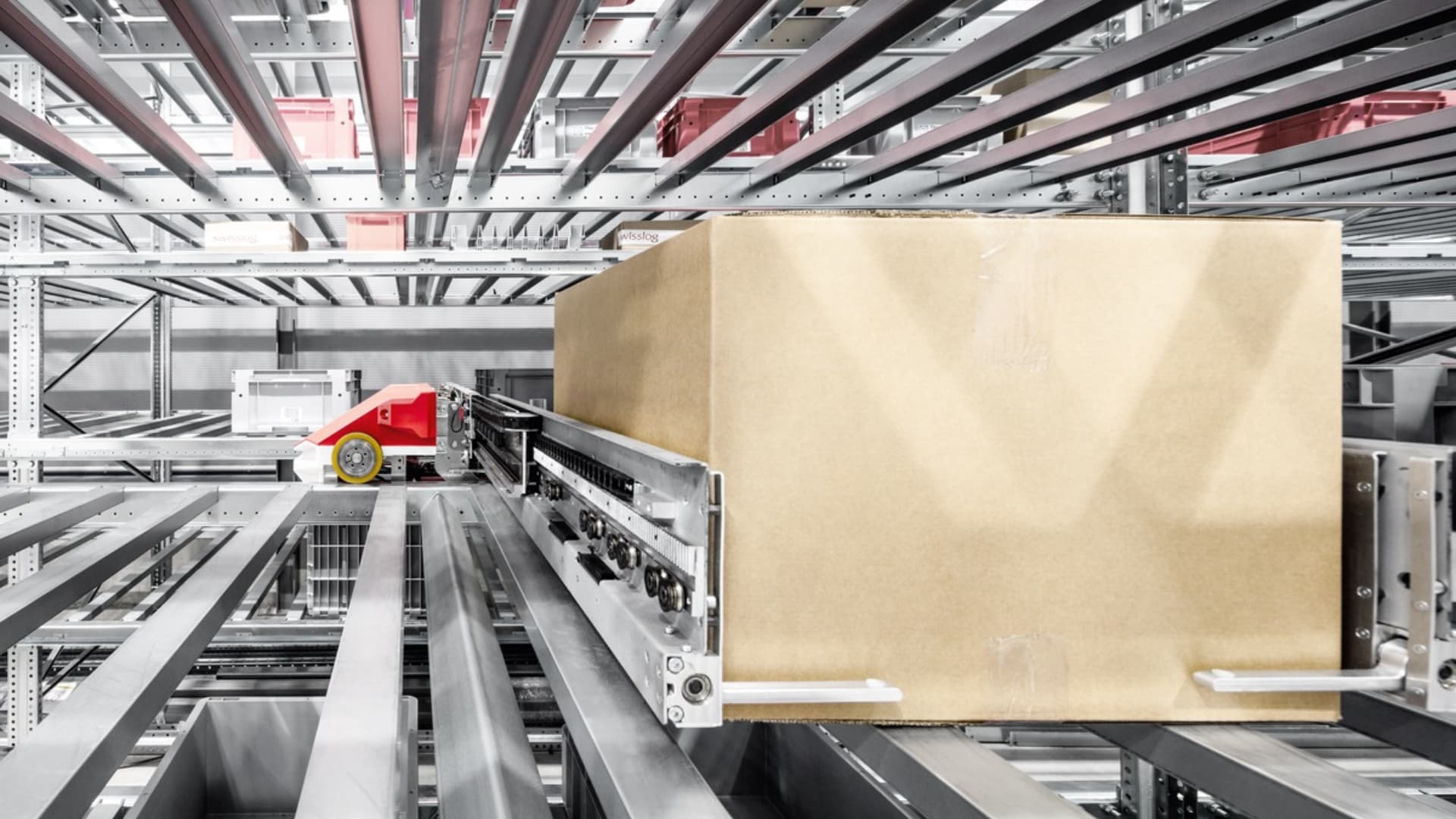 A red toy car is on a conveyor belt with a box.