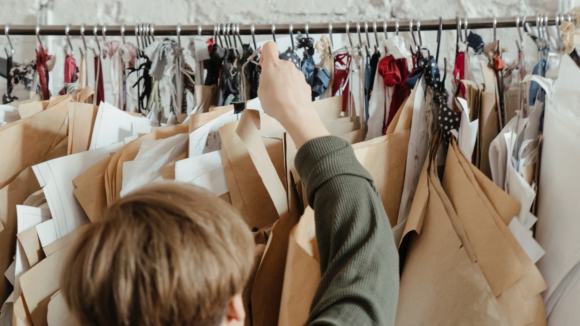 A person with a green shirt is reaching for a hanger.