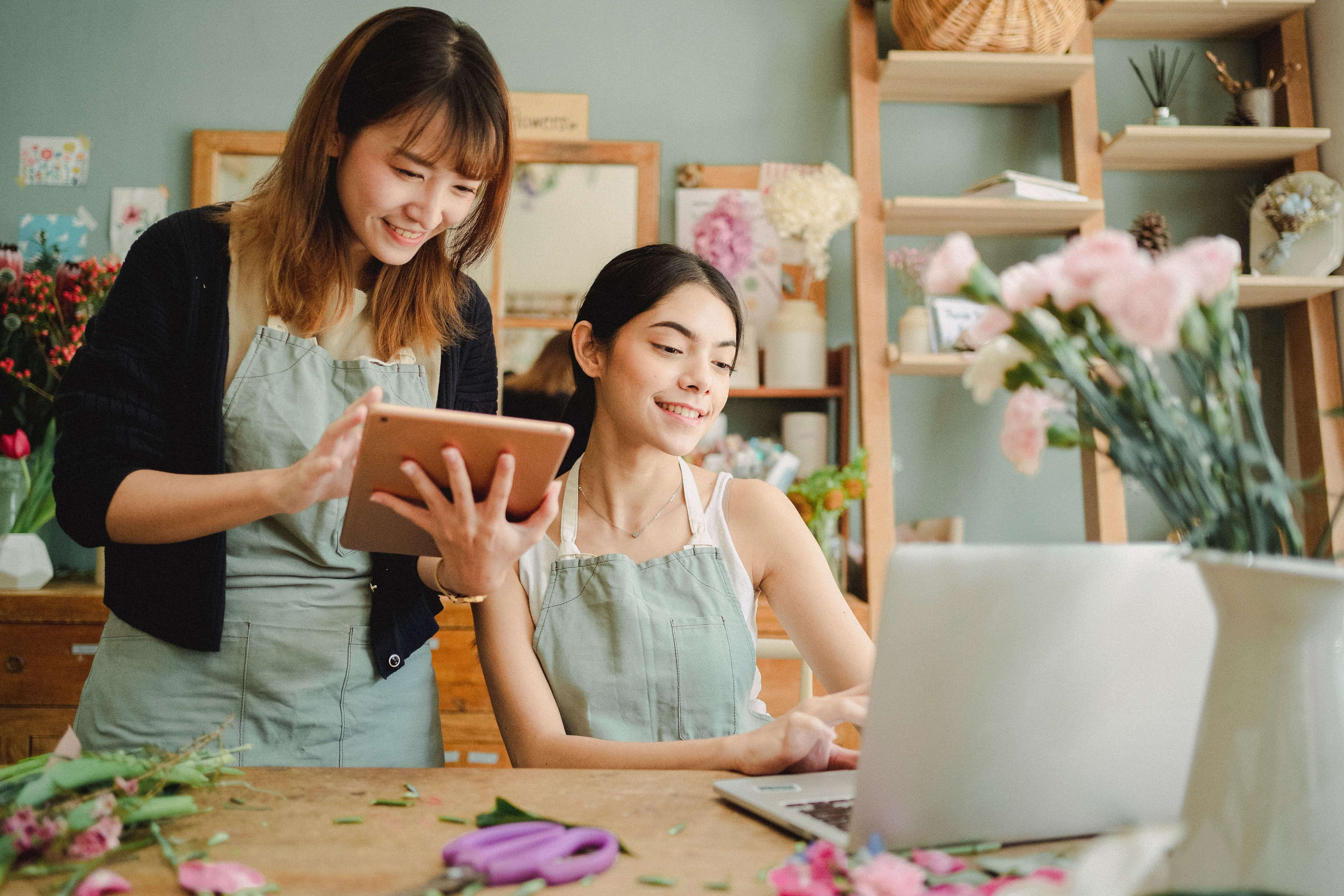 Two women are smiling while looking at a laptop.