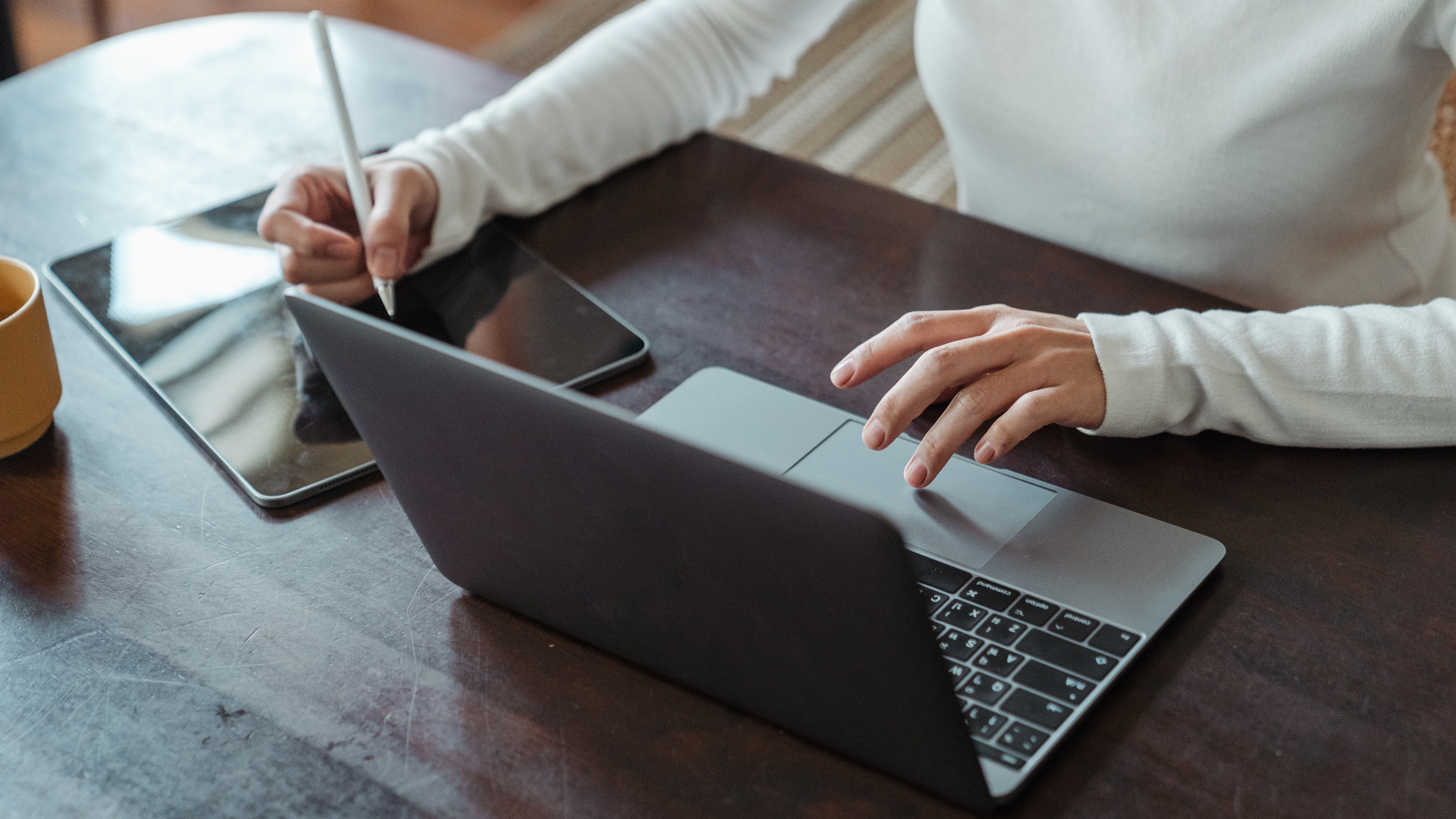 A woman is typing on a laptop with a keyboard in front of her.