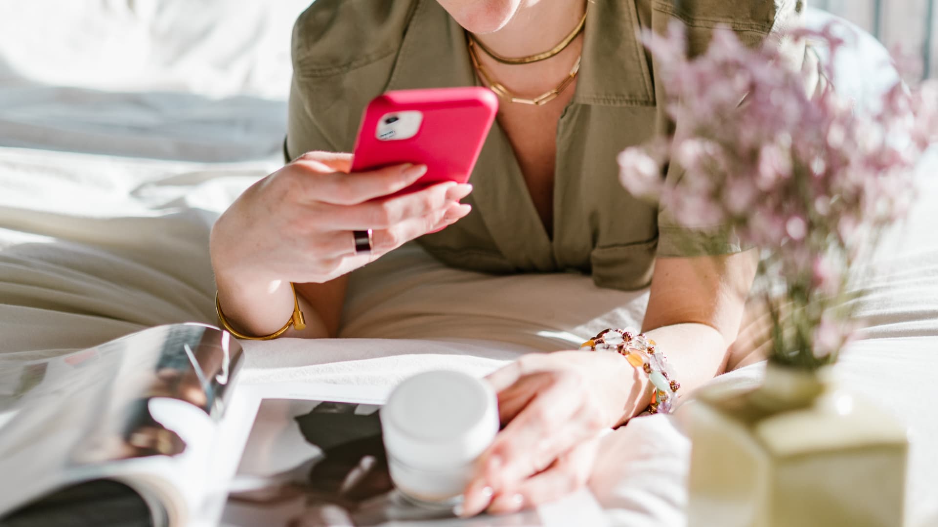 A woman holding a pink cell phone.